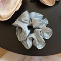 Vue détaillée du chouchou en satin bleu clair avec texture soyeuse et design plissé élégant - Bleu clair