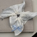 Elegante witte kant scrunchie met lichtblauwe strik en parel op een boek - Blauwe Vierkante Strik Stijl