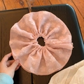 Detail of a large pink floral textured scrunchie made of light chiffon on a wooden surface - Pink