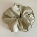 Detailed close-up of bean green fabric scrunchie texture with a small white side label - Green