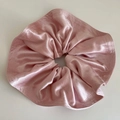 Detail of elegant pink satin scrunchie showing glossy silk texture and petal folds - Pink
