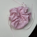 Nahaufnahme von hellrosa Falten-Scrunchie mit zarten Bandschleifen und glänzendem Stoff - Rosa