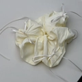 Nahaufnahme von cremefarbenem Scrunchie mit weißer Schleife und feiner Stoffstruktur - Milchiges Gelb