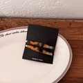 Detail view of a pair of tortoiseshell acetate hair clips on a black card display - Dark Tortoiseshell