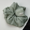 Primer plano de un coletero de satén verde claro con etiqueta tejida Hand Made - Verde