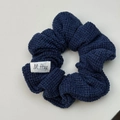 Detailaufnahme des dunkelblauen Strick-Haargummis mit Stofftextur und gewebtem Etikett - Marineblauer Strick-Haargummi (XY-1779) / Marineblau Scrunchie