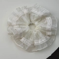 Detail eines weißen Rüschen-Haargummis aus leichtem Organza-Stoff mit feiner floraler Stickerei - Beige