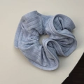 Detailed texture of light blue ribbed knit fabric scrunchie with elastic ruffled edges - Blue