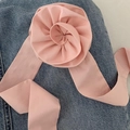 Detailansicht eines 3D hellrosa Stoffrosen-Haargummis mit langem Band auf Denim-Hintergrund - Rosa