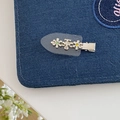 Detailansicht der silbernen Blumen-Haarspange mit bunten Strasssteinen auf Denim-Hintergrund - Transparent