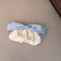 Detail of light blue silk bow hair clip with pleated cream satin fabric on beige textile - Blue