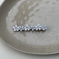 Macro shot of sparkling silver flower hair clip with zirconia stones on a ceramic tray - Five-Petal Flower Row Style (Model E)
