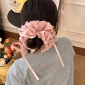 Détail d'un chouchou en dentelle rose avec rubans de soie sur un chignon élégant - Rose