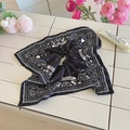 Detail van zwarte Paisley haarelastiek op witte tegels met zachte verlichting - Zwart