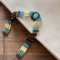Detailed macro view of Bohemian multilayer turquoise and wood bead necklace on wood table - Three-row Turquoise Beaded Style (A)