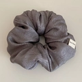 Detailed macro view of smokey gray textured fabric scrunchie with handmade label - Gray