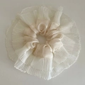 Macro detail of beige ballet style satin scrunchie with pleated lace edge and texture - Off-white