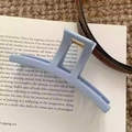 Macro detail of a light blue matte shark hair clip with gold metal spring mechanism - Bar Style