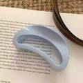 Detailed view of a light blue minimalist hair claw clip placed on an open book - Semicircle Style