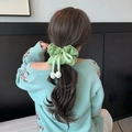 Détail d'un chouchou vert menthe avec nœud et boutons de fleurs sur une queue de cheval - Vert