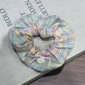 Détail d'un chouchou à carreaux avec nœud rose et étiquette Hand Made sur livre - Chouchou à Carreaux