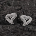 Dettaglio di orecchini a cuore in argento con zirconi scintillanti su sfondo materico - Argento