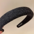 Detail shot of solid black wool headband showing handmade tag and soft fiber texture - Black