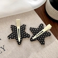 Dettaglio di fermagli per capelli a forma di stella a pois neri su tessuto beige - Stile Stella Nera