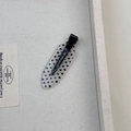 Gros plan d'une pince à cheveux à pois noirs et blancs en acrylique avec clip bec de canard - Modèle Ovale Blanc