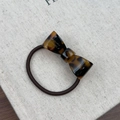 Macro detail of tortoiseshell acetate bow hair tie with gold Handmade engraving text - Dark Leopard Print