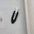 Vue détaillée d'une barrette à pois noirs et blancs dans un coffret de présentation - Modèle Ovale Noir