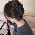 Dettaglio di un fermaglio per capelli in peluche grigio su una donna al coperto - L Nero
