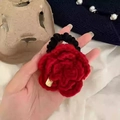 Dettaglio di un elastico per capelli con rosa rossa all'uncinetto e targhetta d'oro - Elastico per capelli