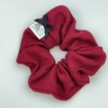 Dettaglio scrunchie in maglia rosso scuro con fiocco di raso nero ed etichetta - Rosso