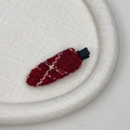 Detailed view of red tweed hair clip with gold metallic threads on a display tray - Red