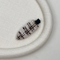 Detaillierte Makroansicht der Tweed-Stofftextur und des Goldfadens auf der Haarspange - Beige