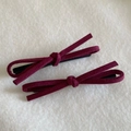 Detail of red suede bow hair clips with black metal duckbill clips on soft fabric - Burgundy