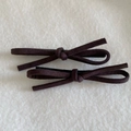 Detail view of two brown suede bow hair clips on a soft cream plush background - Dark Coffee