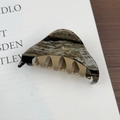 Detail view of acetate shark hair clip featuring marble texture and gold handmade engraving - Brown