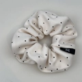 Detail showing soft cotton polka dot scrunchie with black woven bow logo tag - Hair Tie / Off White