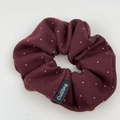 Detailed texture of burgundy polka dot scrunchie fabric with brand woven label - Hair Tie / Red