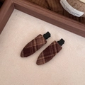 Primer plano de horquillas de tela a cuadros marrones con clips de metal negro sobre madera - Rayas marrones