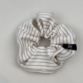 Détail d'un chouchou rayé montrant la texture du tissu et l'étiquette logo - Blanc Cassé