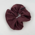 Detailopname van de donkerrode gestreepte stof en het zwarte merklabel op de scrunchie - Rood