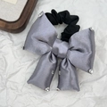 Makroaufnahme von grauem Seiden-Scrunchie mit funkelnden Strasssteinen und Gummiband - Grauviolett
