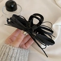 Detail of black ribbon bow hair claw with a silver heart pendant held by a model - Black Bow Claw Clip