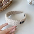 Dettaglio della fascia in maglia beige con trama a trecce ed etichetta True Fitted - Bianco Sporco