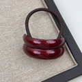 Macro detail of wine red curved resin hair tie with high-elasticity braided brown band - Double Arc Red
