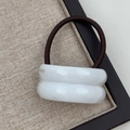 Close-up of white curved resin hair tie with gold label detail on linen tray - Double Arc White