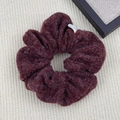 Close-up of deep red plush velvet scrunchie with soft sheepskin texture and logo tag - Hair Tie / Burgundy